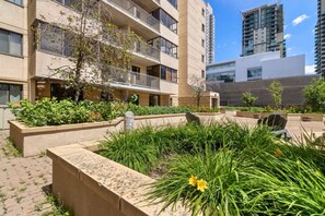 Un edificio residencial de varios pisos con balcones, un patio con plantas y un estilo arquitectónico moderno.
