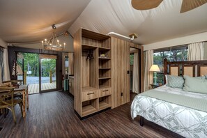 A bedroom with a bed, wooden wardrobe, and a dining area with a table and chairs.