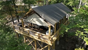 Une cabane en bois dotée d’un balcon, d’un espace salon couvert et d’une petite cuisine extérieure.