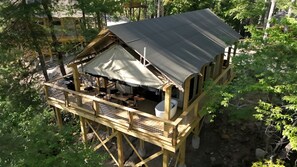 Eine Holzhütte mit Balkon, überdachter Sitzgelegenheit und kleiner Außenküche.
