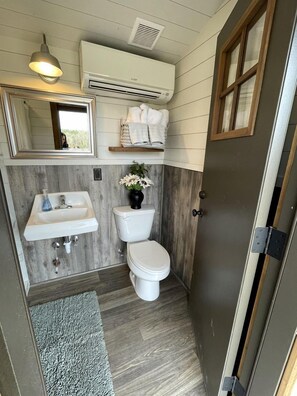 A compact bathroom with a sink, toilet, and mirror.