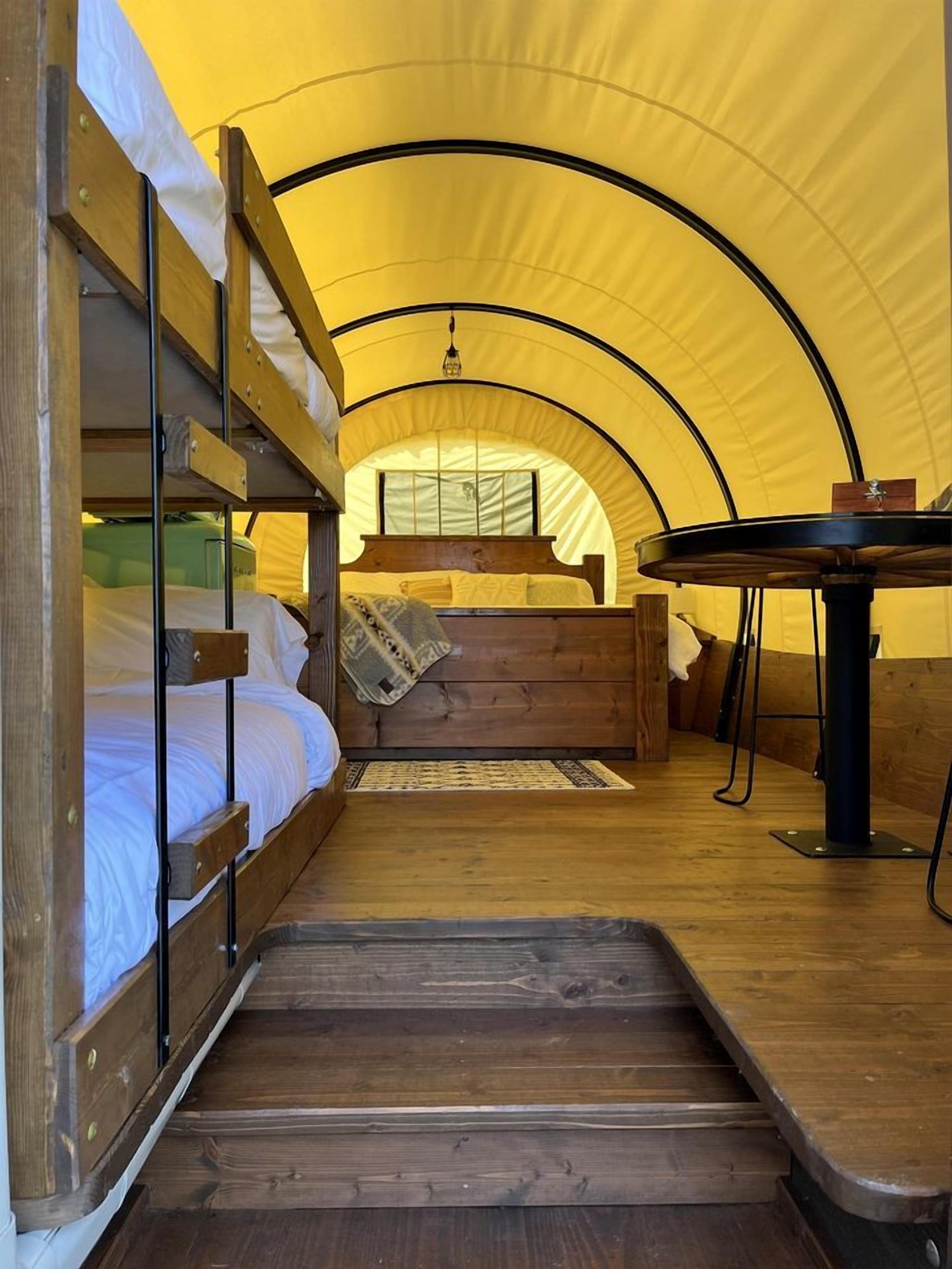 A tented accommodation with bunk beds, a central seating area, and a dining table.