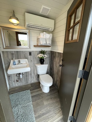 A compact bathroom with a sink, toilet, and mirror.