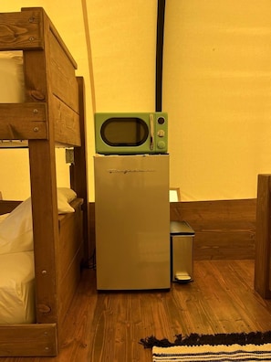 Eine kleine Küchenzeile mit Mikrowelle und Kühlschrank in einem Raum mit Holzmöbeln.