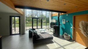 En moderne stue med sofa, pejs og store vinduer.