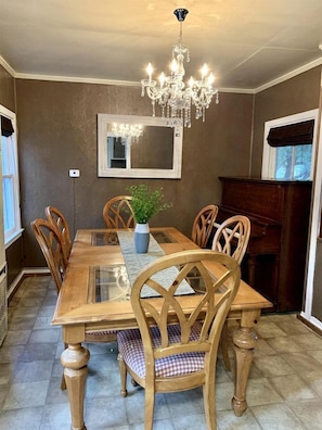 Ein Esszimmer mit Holztisch, Stühlen, einer Chandelier und einem Blumentopf.