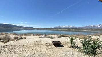 Un espace extérieur abrité, offrant une vue sur un lac et des montagnes, et comprenant un coin salon avec des chaises et une table.