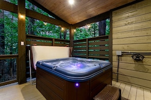 Ein Whirlpool in einer Holzterrasse mit Blick auf Bäume.
