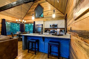 Ein Holzblockhaus-Interieur mit Kücheninsel, Barhocker und Essbereich.
