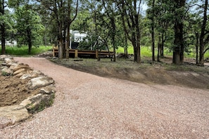 Un sendero de grava que conduce a una estructura de madera rodeada de árboles.