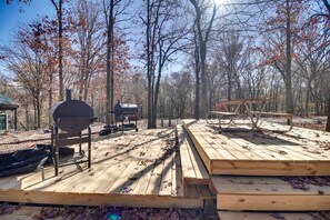 A wooden deck with a grill and picnic table, surrounded by trees. - Cozy Studio Retreat with Scenic 5-Acre Views, Near City Lake & Cherokee Casino in Gentry, Arkansas (Gentry)