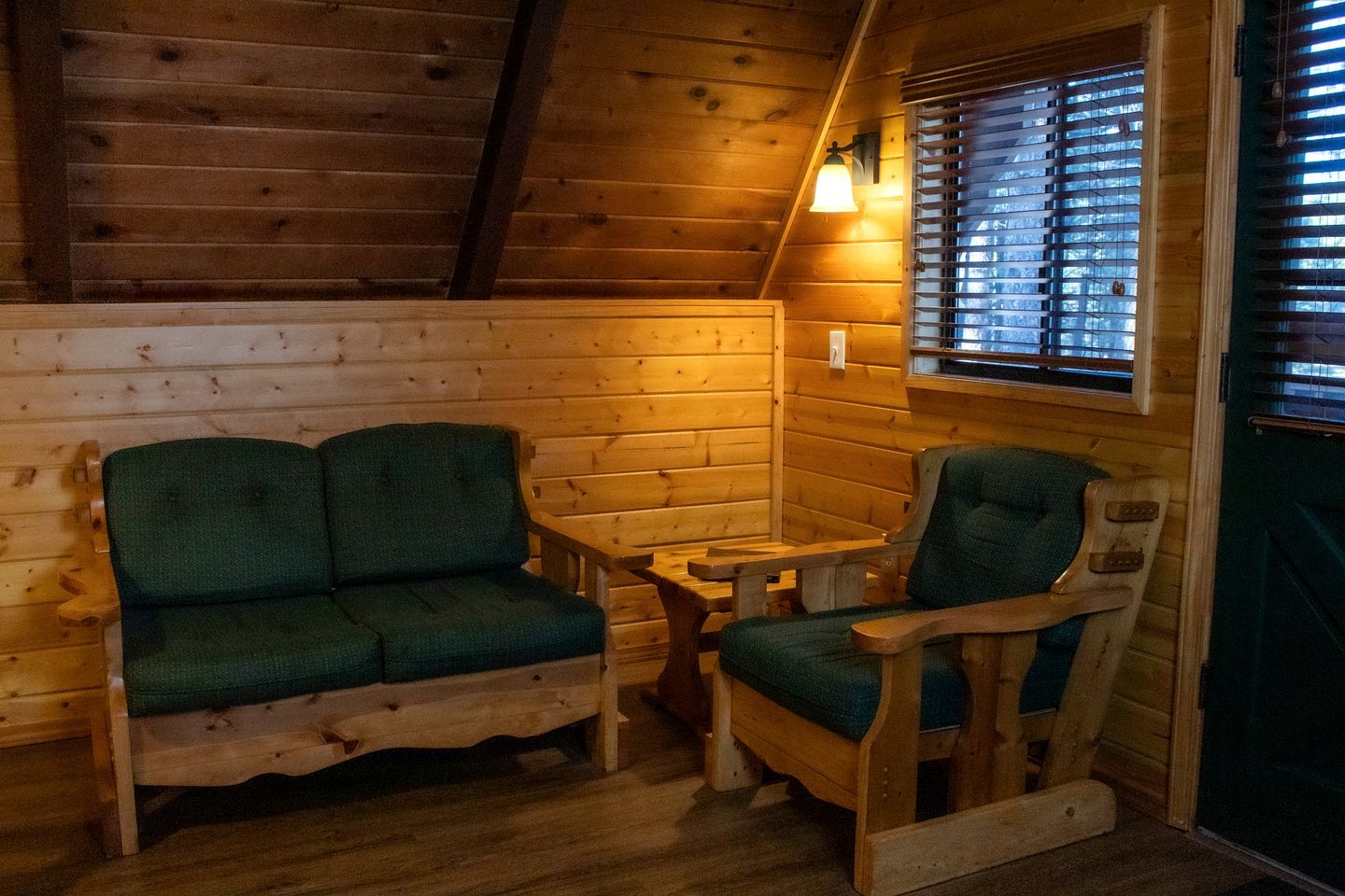 Interior acogedor de una cabaña con un banco de madera, una mesita y una ventana con persianas.