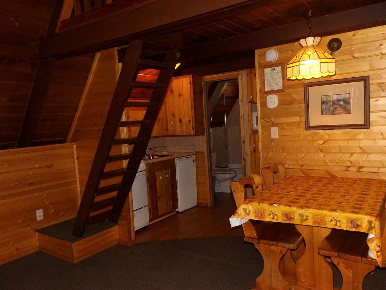 L’intérieur d’un chalet en bois comprend une cuisine, un coin repas et un escalier.