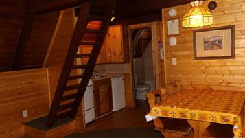L’intérieur d’un chalet en bois comprend une cuisine, un coin repas et un escalier.