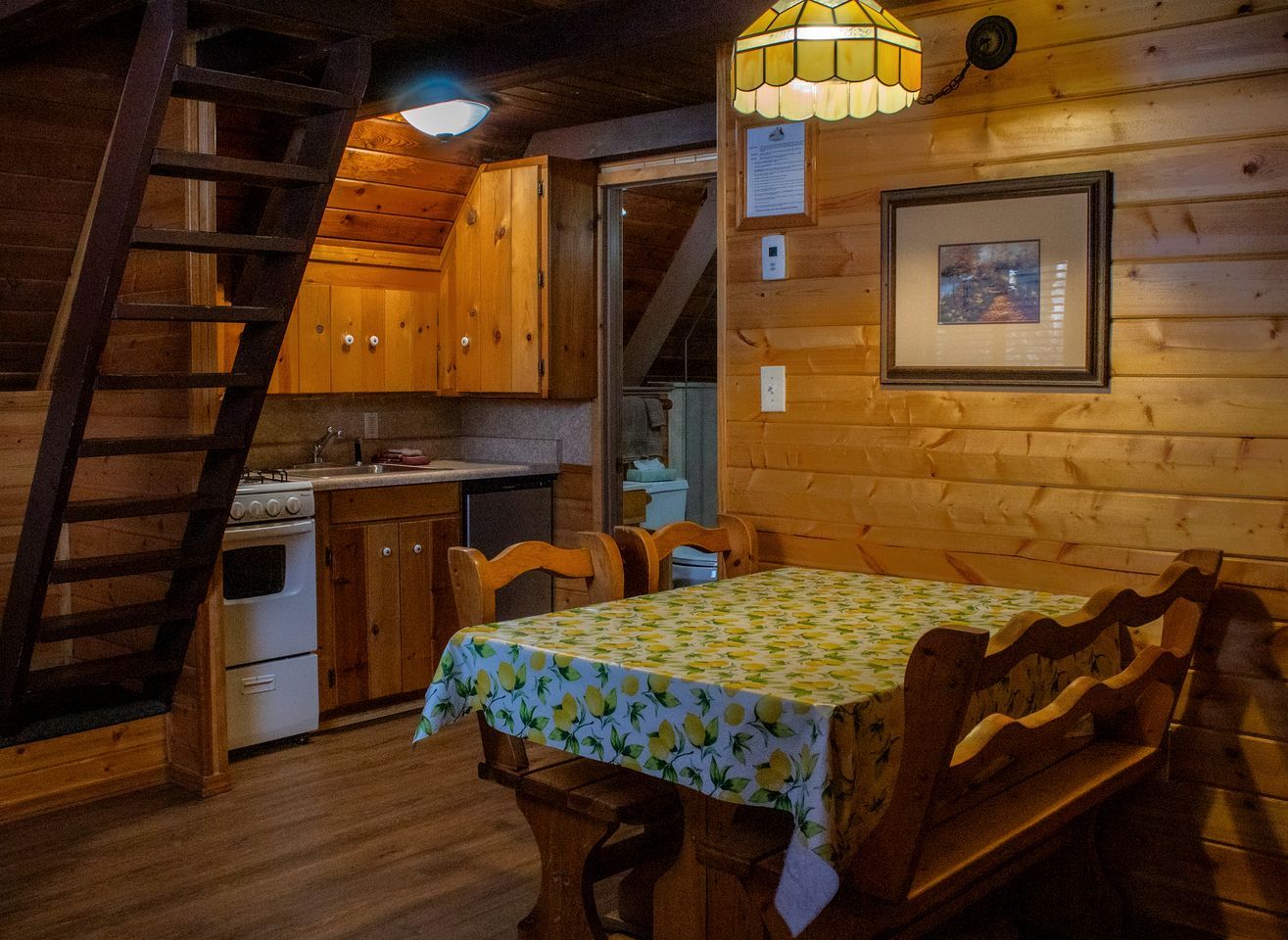 Un interior de madera con una mesa de comedor, sillas, una estufa y una escalera.