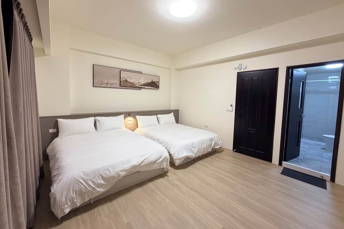 Ein Hotelzimmer mit zwei Betten, einer Deckenleuchte, einer Tür und einem an der Wand befestigten Bild.