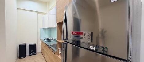 Una cocina moderna con refrigerador de acero inoxidable, gabinetes de madera, horno empotrado y un lavamanos.
