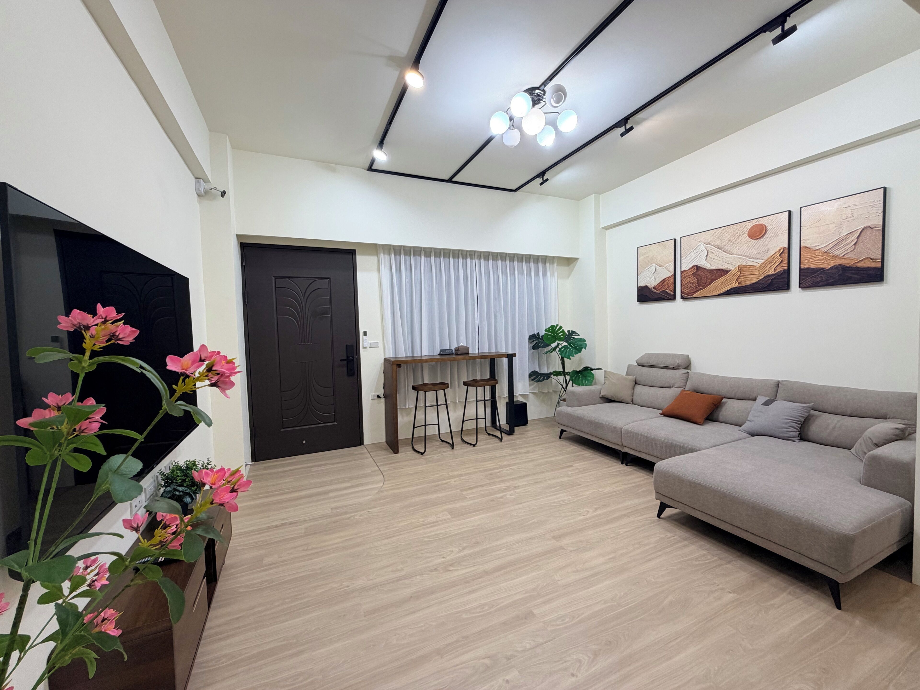 A modern living room with a sofa, a TV, a dining area, and artwork on the wall.
