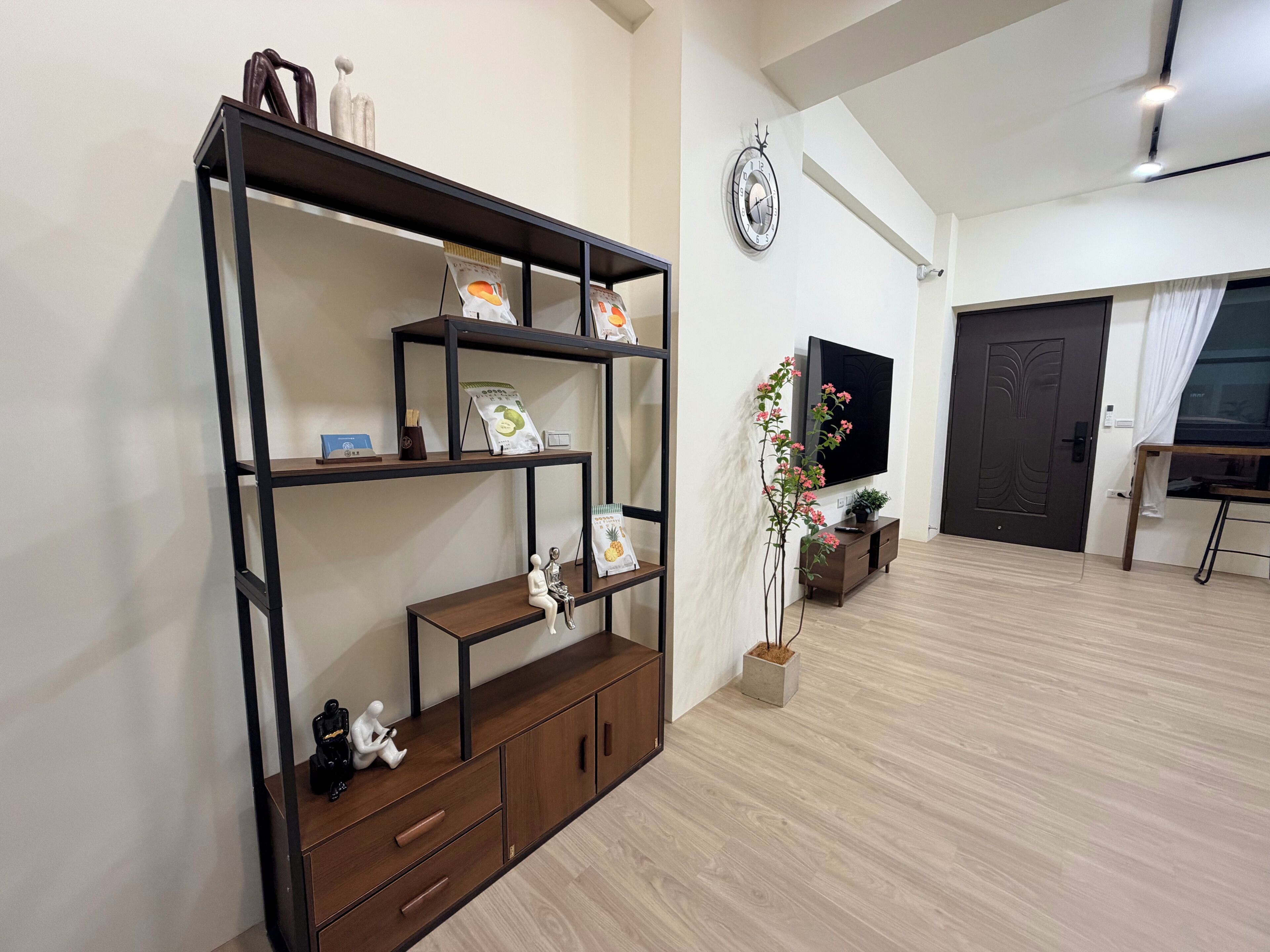 A modern living room with a wooden cabinet, a wall-mounted TV, and a decorative plant.