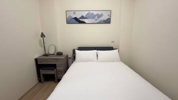 Un dormitorio con cama, escritorio, silla, lámpara, espejo y un cuadro en la pared.