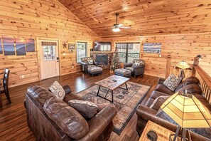 Ein Blockhaushaus-Interieur mit Kamin, Ledersofas, einem Couchtisch und einem Weihnachtsbaum.