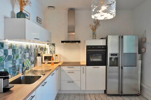 Eine moderne Küche mit weißen Schränken, einem Edelstahl-Kühlschrank, einem Einbauofen und einer Mikrowelle.