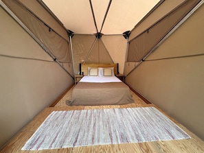 Una habitación con tienda de campaña, una cama, suelo de madera y alfombra estampada.