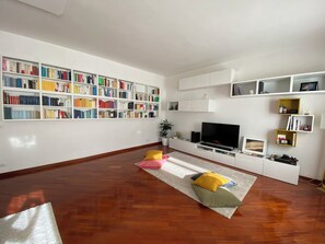 Un soggiorno con una grande libreria, una televisione a schermo piatto e un pavimento in legno.
