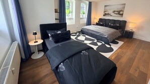 Et moderne soveværelse med en seng, sengeborde, en lampe og et vindue med gardiner.