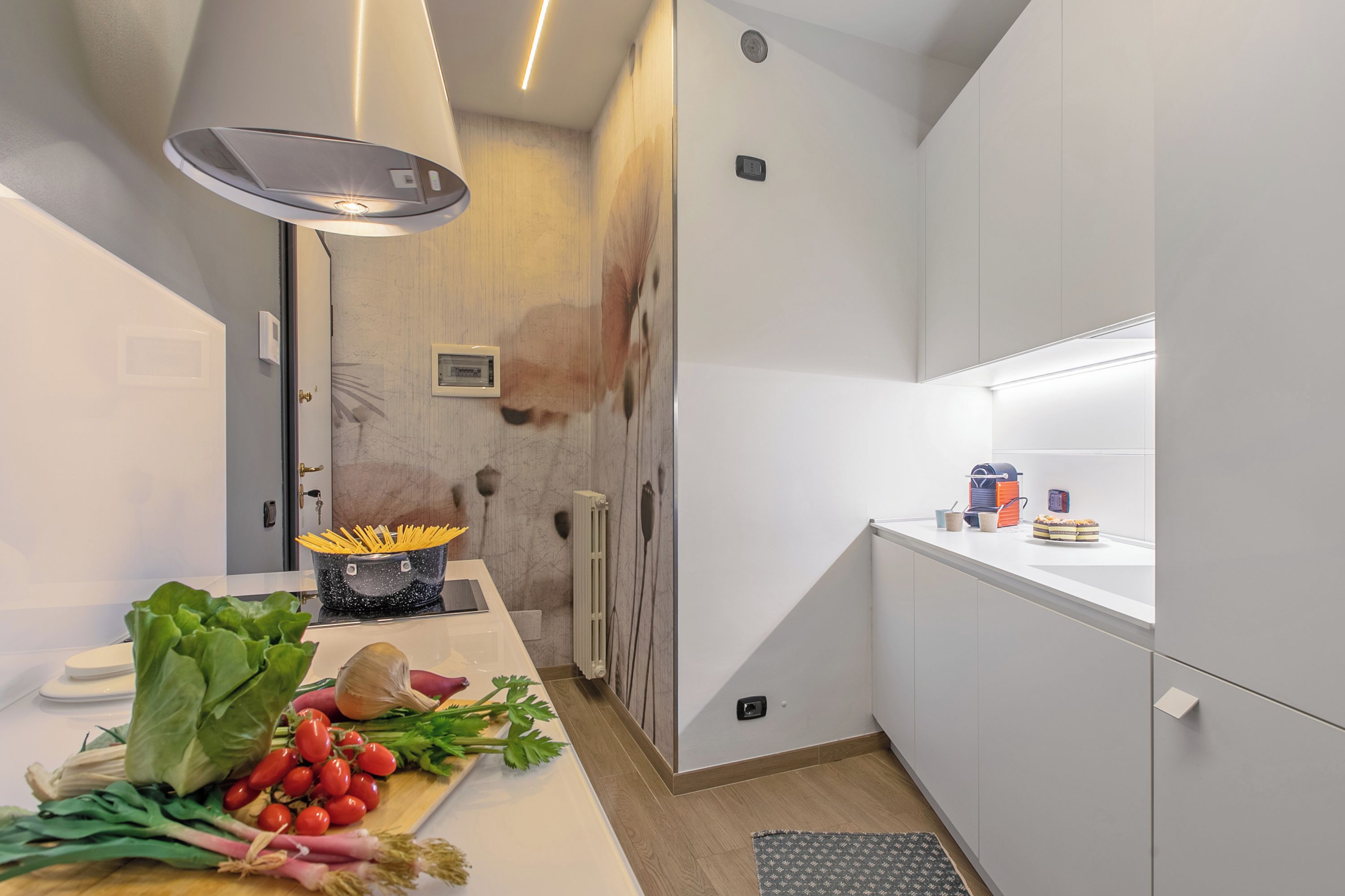 A modern kitchen with white cabinets, a wooden countertop, and a variety of fresh produce.