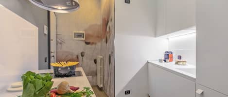 A modern kitchen with white cabinets, a wooden countertop, and a variety of fresh produce.