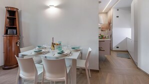 Comedor con una mesa dispuesta para cuatro, sillas blancas, un aparador de madera y una lámpara moderna.
