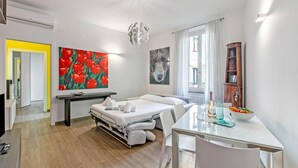 A modern hotel room with a bed, a dining table, a painting of red tulips, a wolf painting, and a wooden cabinet. - Charme Nest Luxury Suite Milan - Isola (Milan)