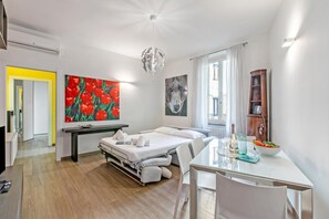 A modern hotel room with a bed, a dining table, a painting of red tulips, a wolf painting, and a wooden cabinet. - Charme Nest Luxury Suite Milan - Isola (Milan)