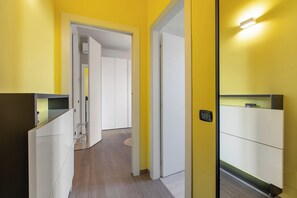 Un couloir aux murs jaunes, aux portes blanches et au plancher en bois.