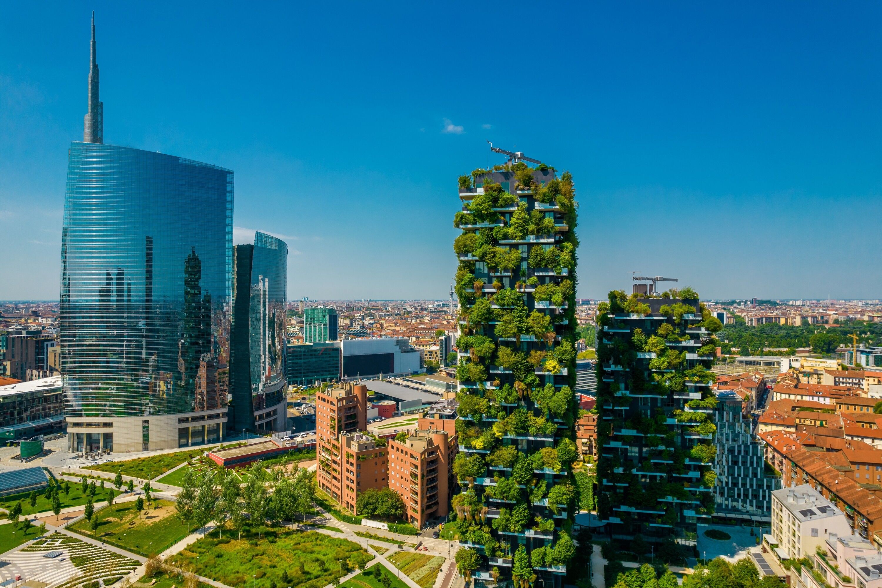 A modern cityscape with high-rise buildings, including a skyscraper with a unique vertical garden design.