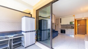 Een modern appartement met een kitchenette, een eethoek met een tafel en stoelen, en een schuifdeur naar een woonruimte.