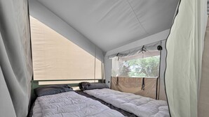 A tented room with two beds, a window, and a view of trees. - Safari Tent Glamping with Riverside Relaxation Space in Blacksburg, Virginia (Blacksburg)