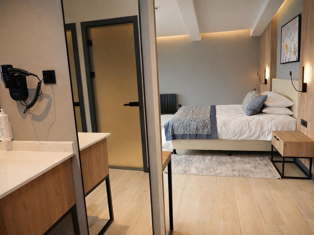 Una habitación de hotel moderna con cama, mesita de noche y escritorio con silla.