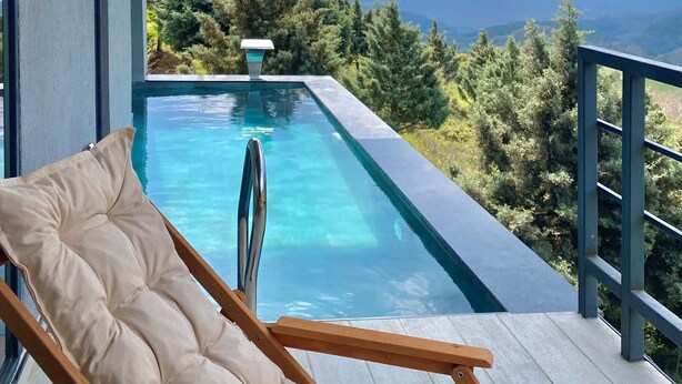 Ein Balkon mit Pool, Liegestuhl und Bergblick.
