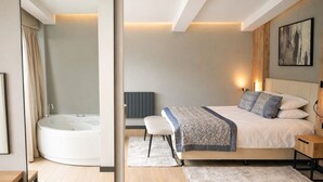Ein modernes Schlafzimmer mit einem großen Bett, einem Nachttisch, einem Wandbild und einer integrierten Badewanne.