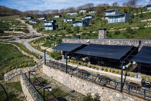 Una zona residencial en una ladera con casas modernas, zonas de estar al aire libre y un muro de contención de piedra.