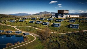 Ein modernes Resort mit mehreren Blockhütten, einem zentralen Gebäude und einem See.