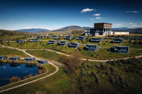 A modern resort with multiple cabins, a central building, and a lake.