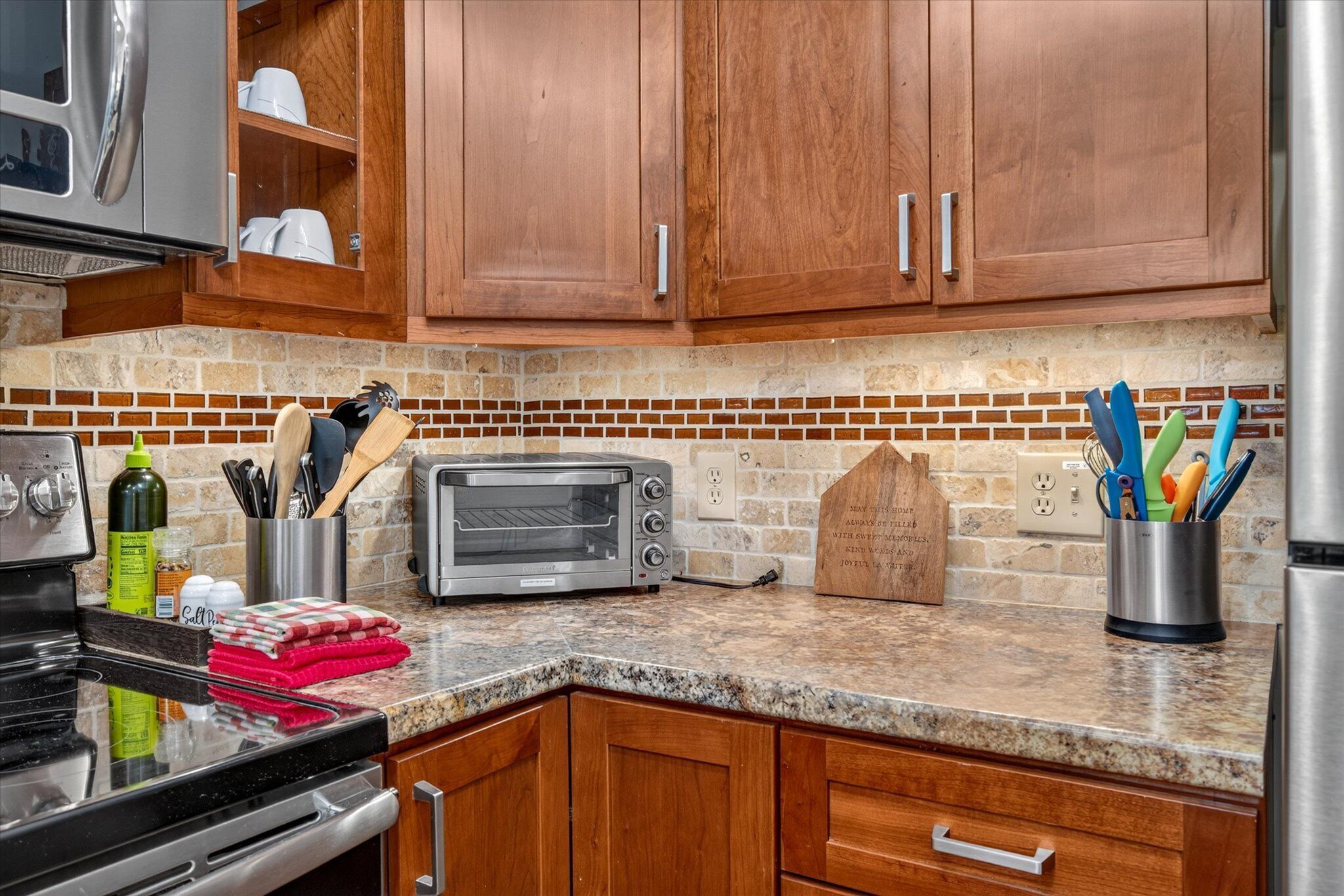 A kitchen with wooden cabinets, a toaster, a microwave, and a brick backsplash.