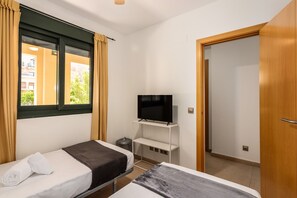 A hotel room with two beds, a TV on a stand, a window with curtains, and a door. - Playa Marina - Punta del Moral Beach PPHM208P32 (Punta del Moral)