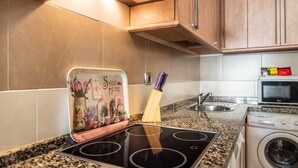 Une cuisine équipée d’une cuisinière, d’un four à micro-ondes et d’un lave-linge.