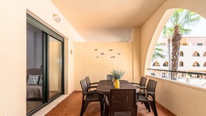 Un balcon avec une table à manger, des chaises et un mur décoratif orné d’autocollants représentant des poissons.