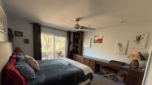A bedroom with a bed, desk, and ceiling fan.