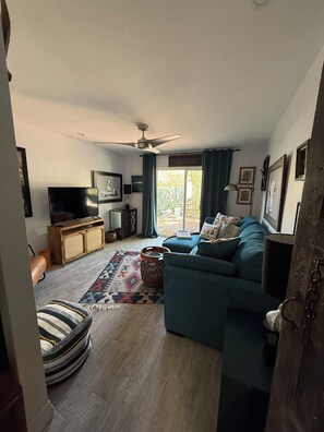Ein Wohnzimmer mit einer Couch, einem Fernseher und einem Deckenventilator.
